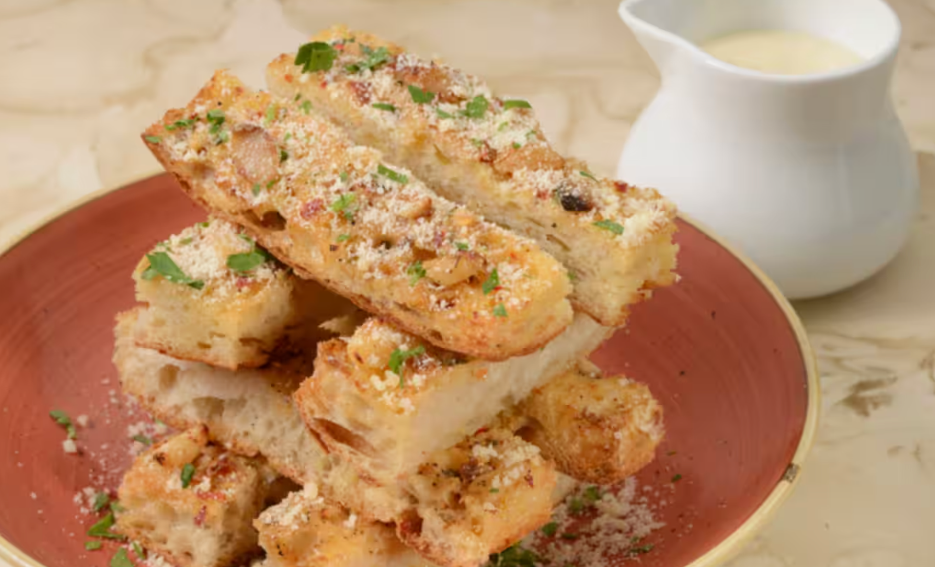 Crispy French toast sticks arranged on brown plates with a small bowl of maple syrup for dipping.