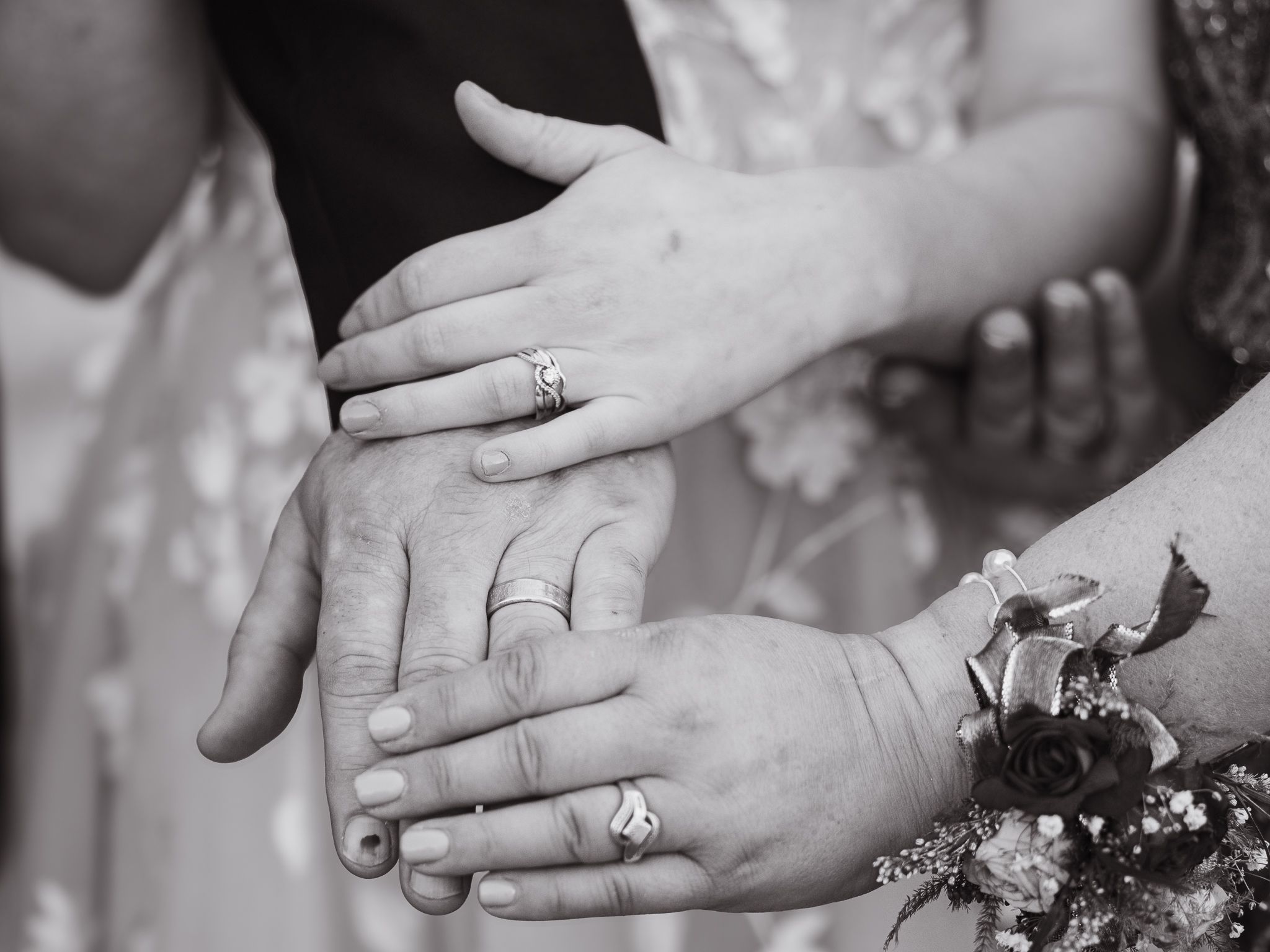 Close-up black and white photo of hands displaying wedding rings.