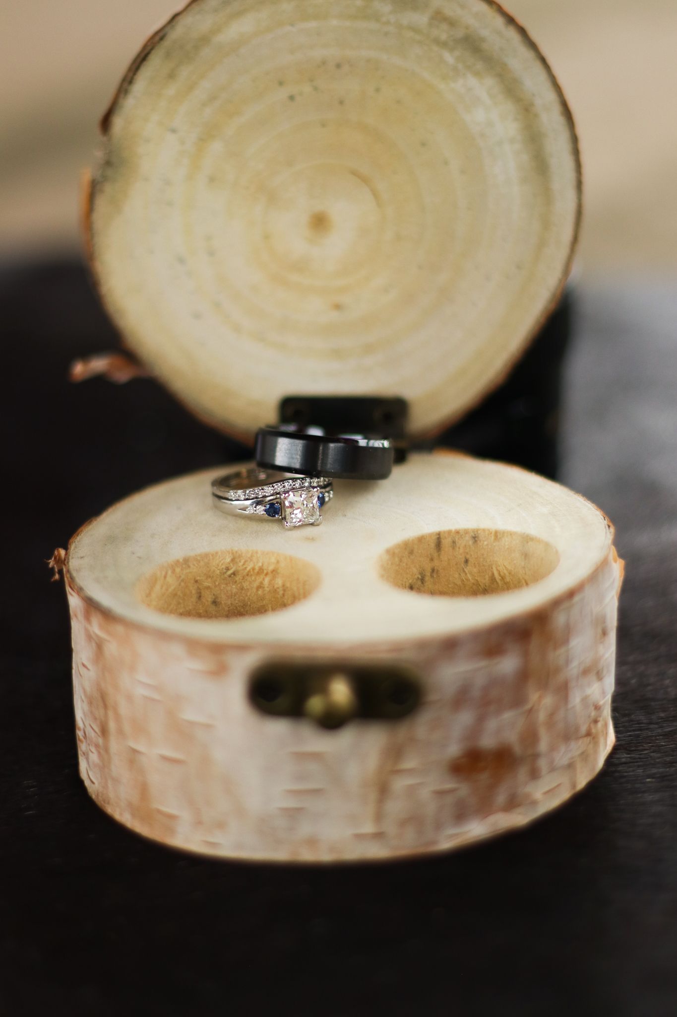 Wedding rings nestled in a rustic birch wood ring box with a hinged lid.