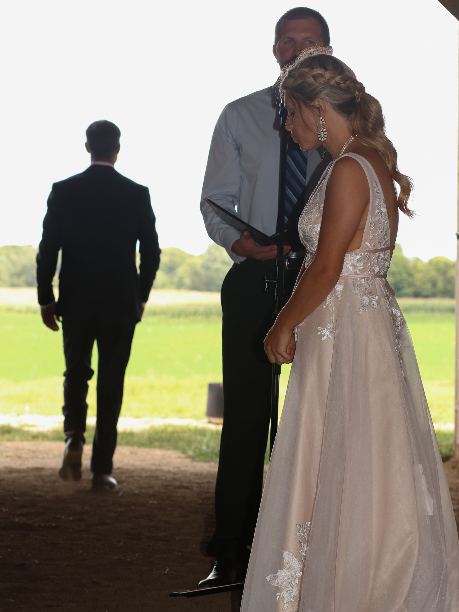 A wedding ceremony in progress under a rustic barn structure with natural lighting.