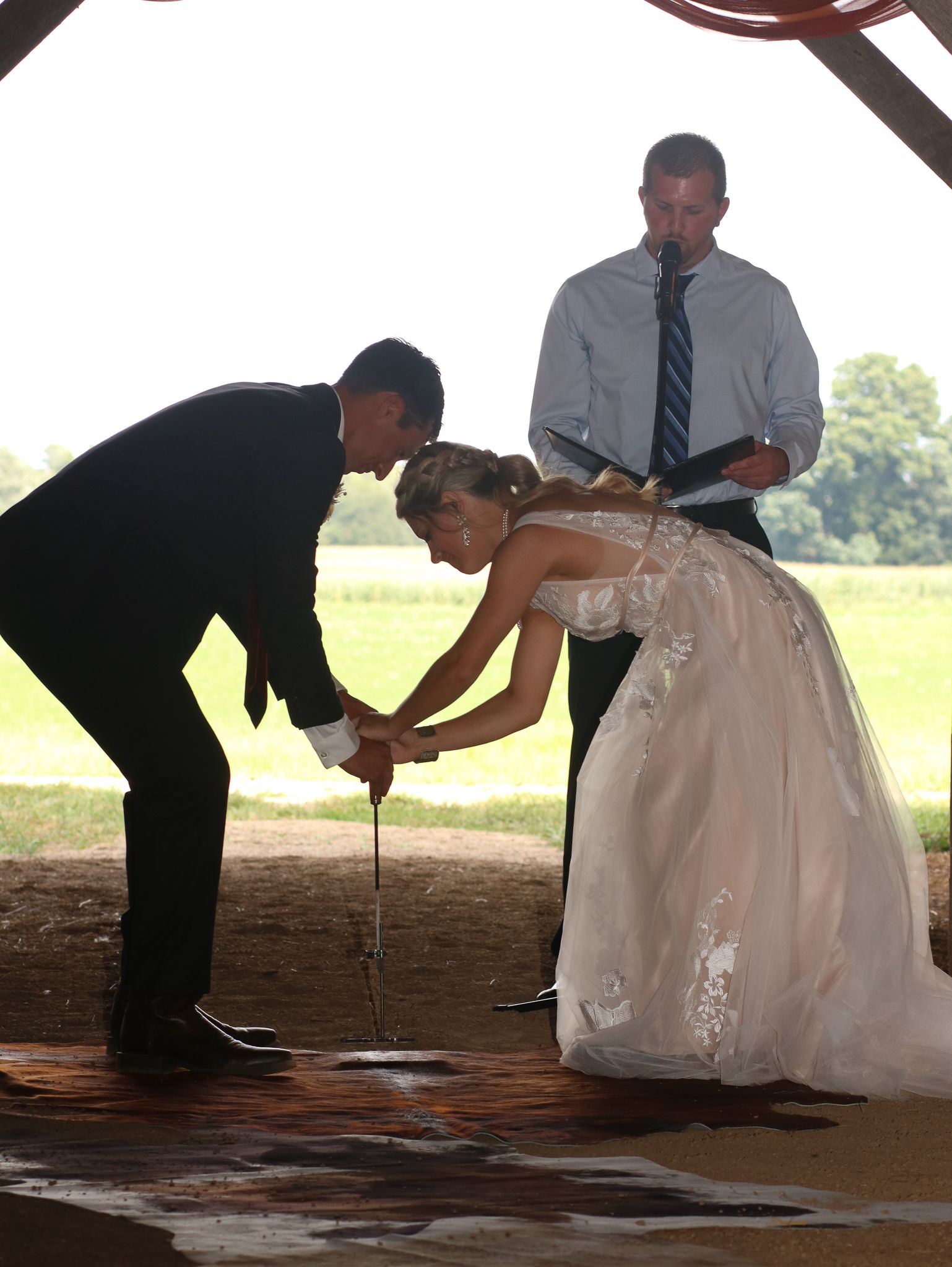 A wedding ceremony tradition being performed under a rustic wooden structure.