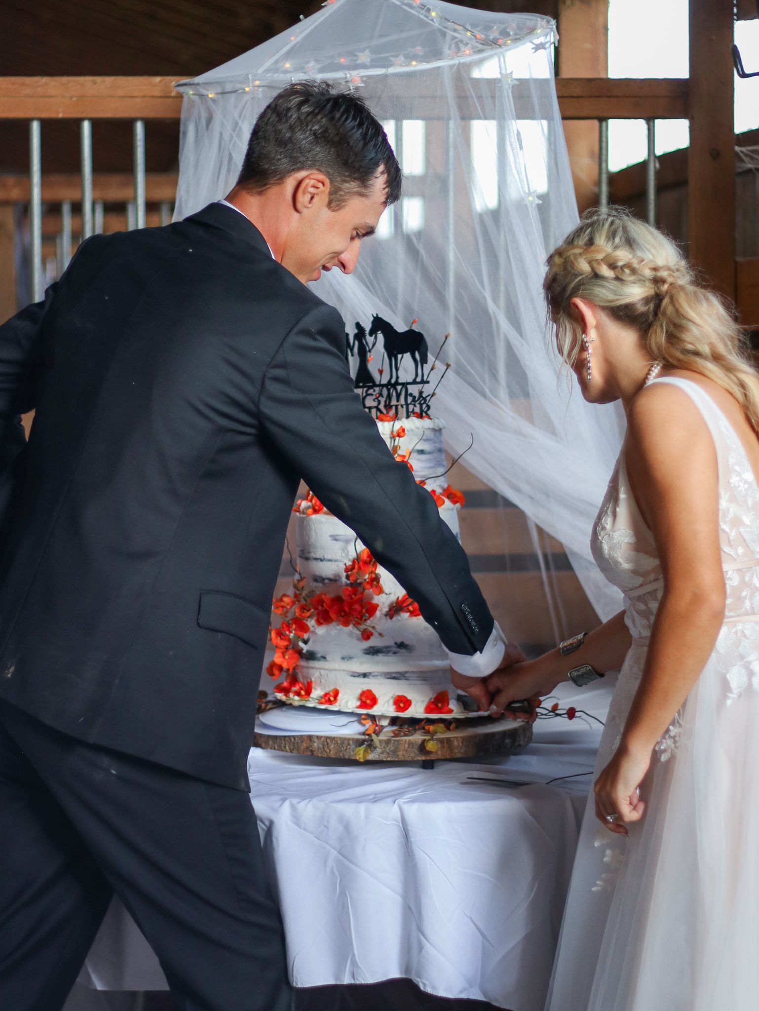 Wedding couple cutting their white and red decorated cake together.