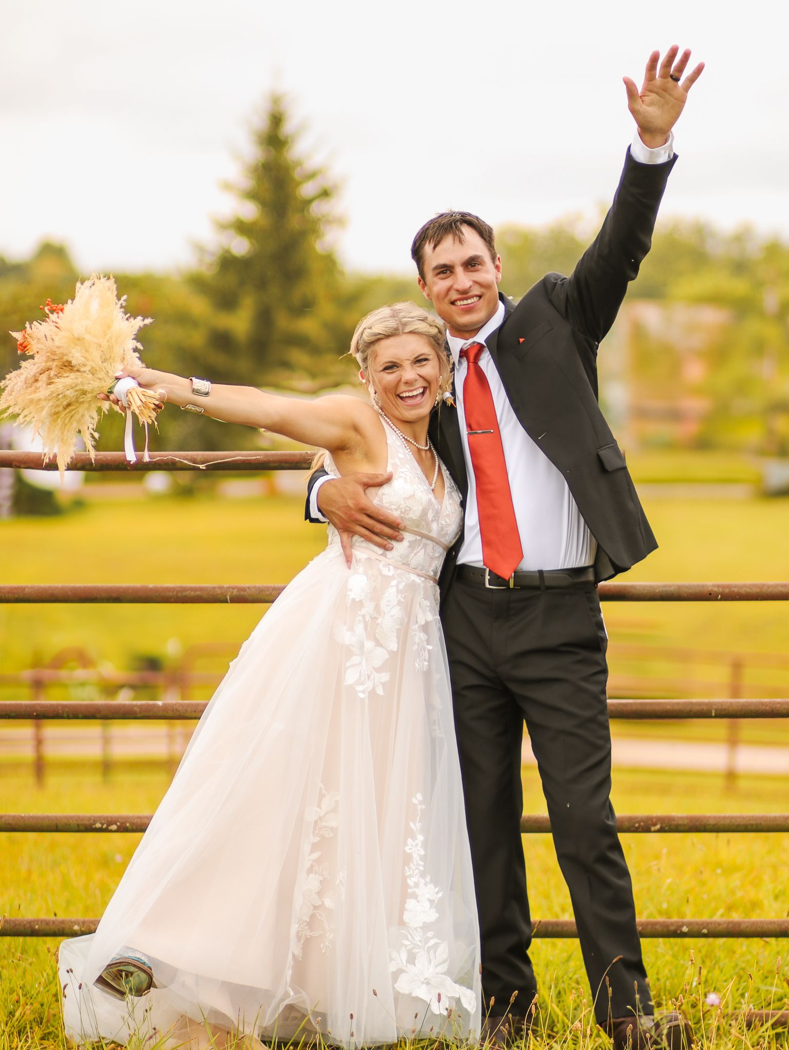 Joyful celebration moment with arms raised against rustic farm backdrop.