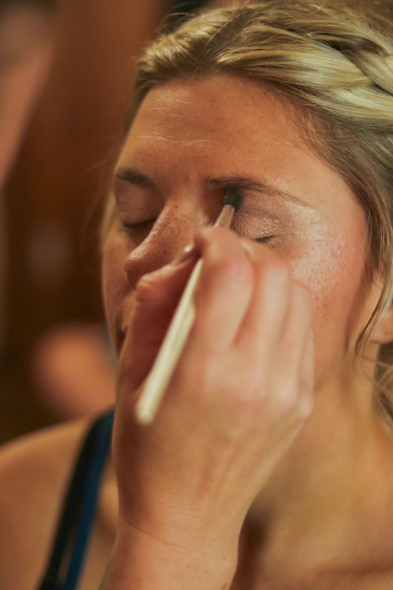 Makeup being applied to closed eyes during wedding day preparations.