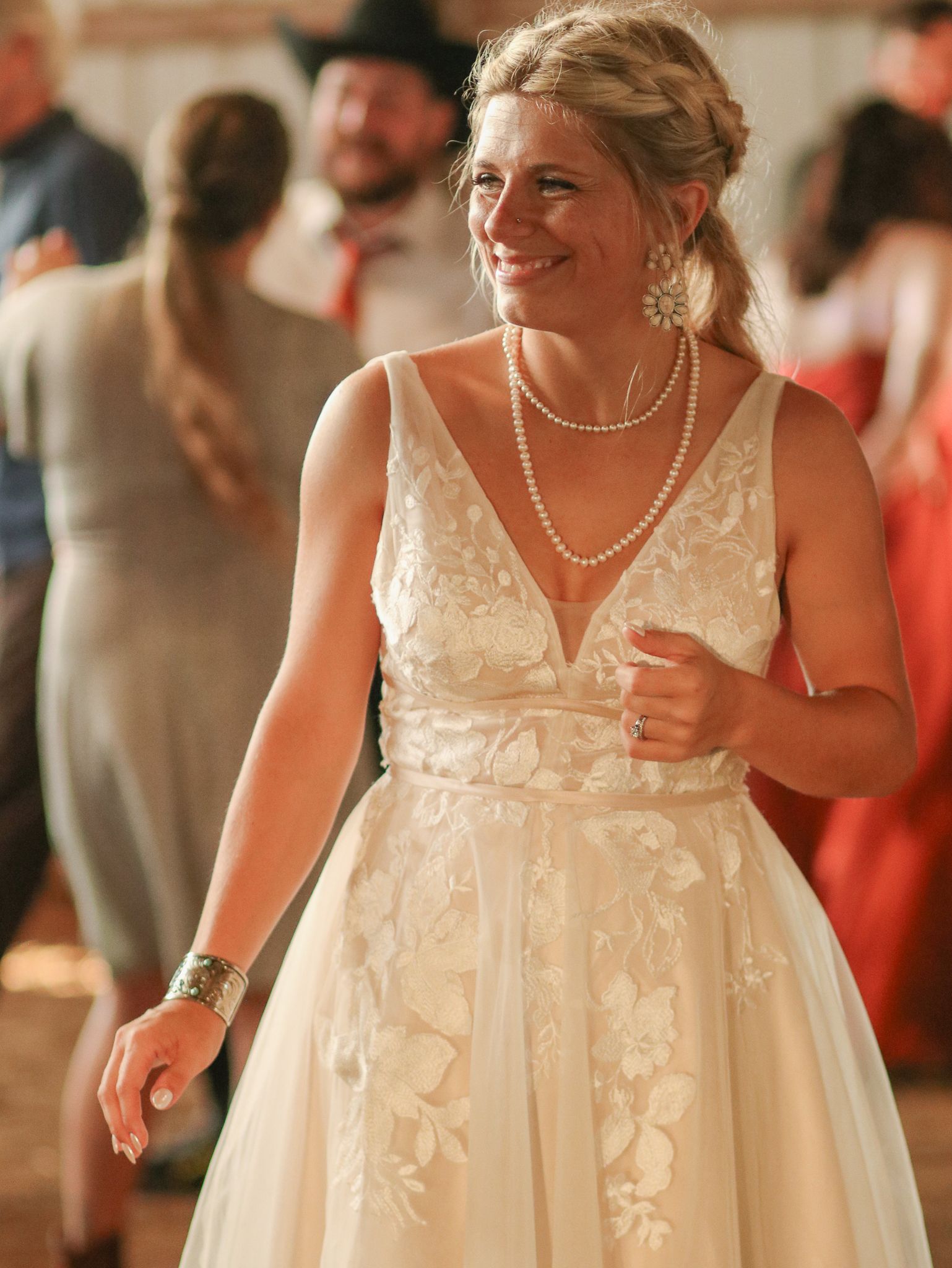 A bride in a beautiful white lace dress smiles during her wedding reception.
