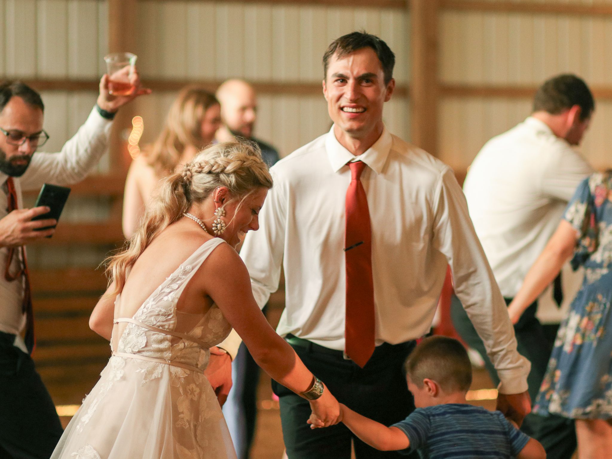 Wedding guests dancing together at a reception in a rustic venue.