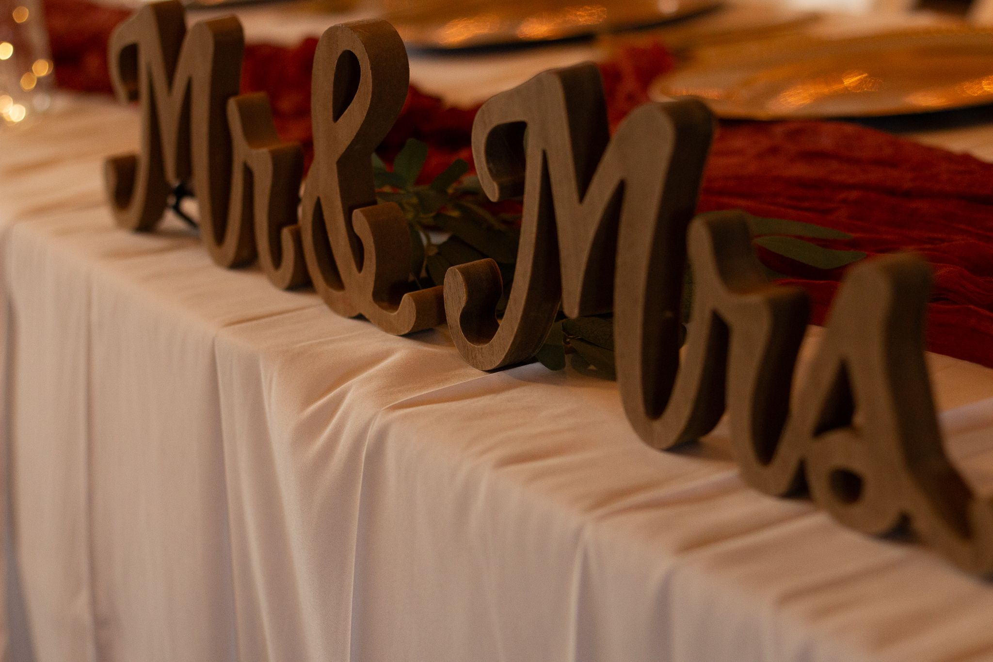 Wooden Mr. and Mrs. letters displayed on a white tablecloth at a wedding reception.