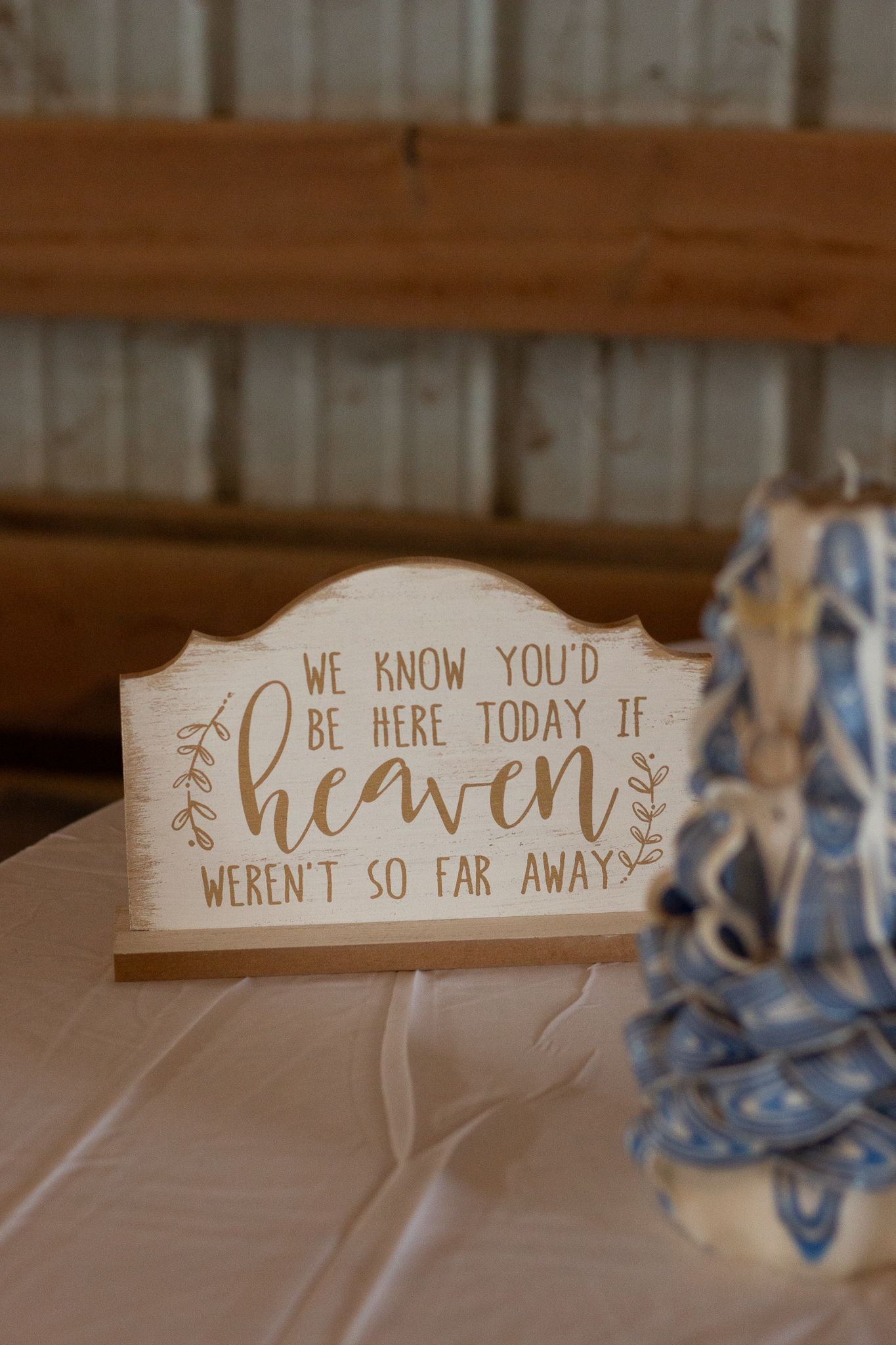 A wooden memorial sign reads 'We know you'd be here today if heaven weren't so far away'.