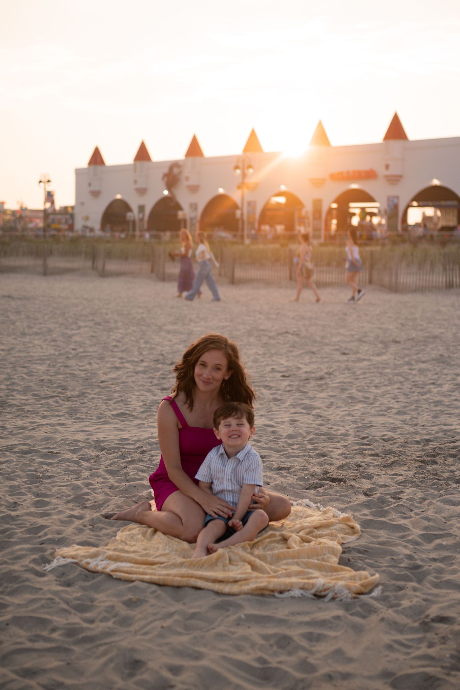 People enjoying sunset on a beach near white castle-like structures.