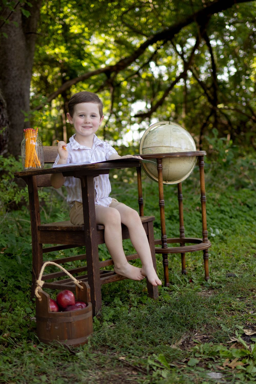 A vintage school desk scene with chalkboard and globe props set up in a wooded area.