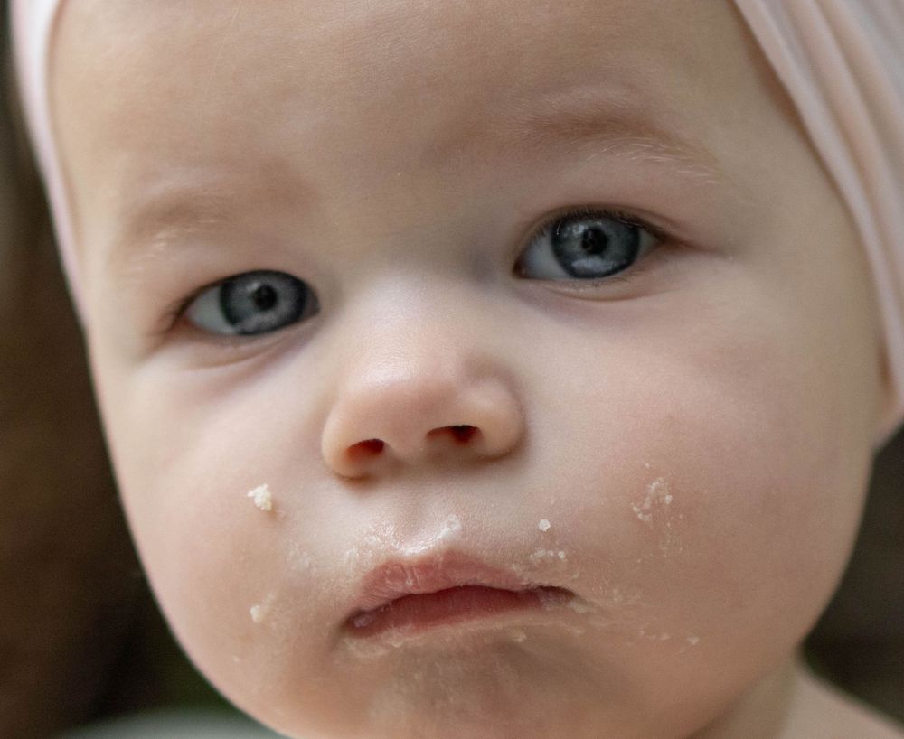 A close-up portrait showing bright blue eyes and messy face after eating.