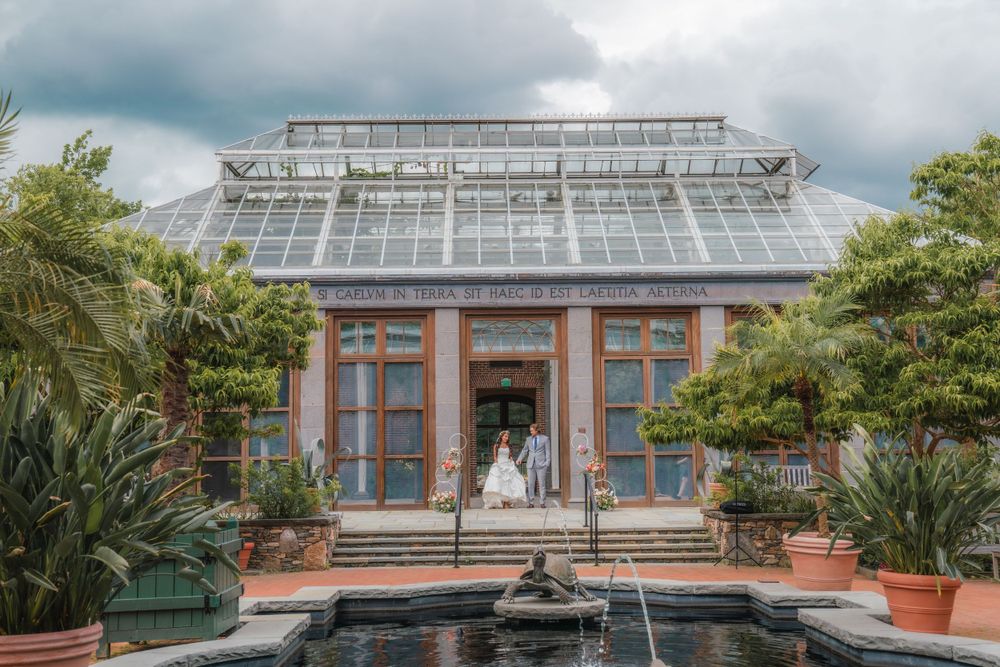 Glass conservatory wedding venue with tropical plants and reflection pool.