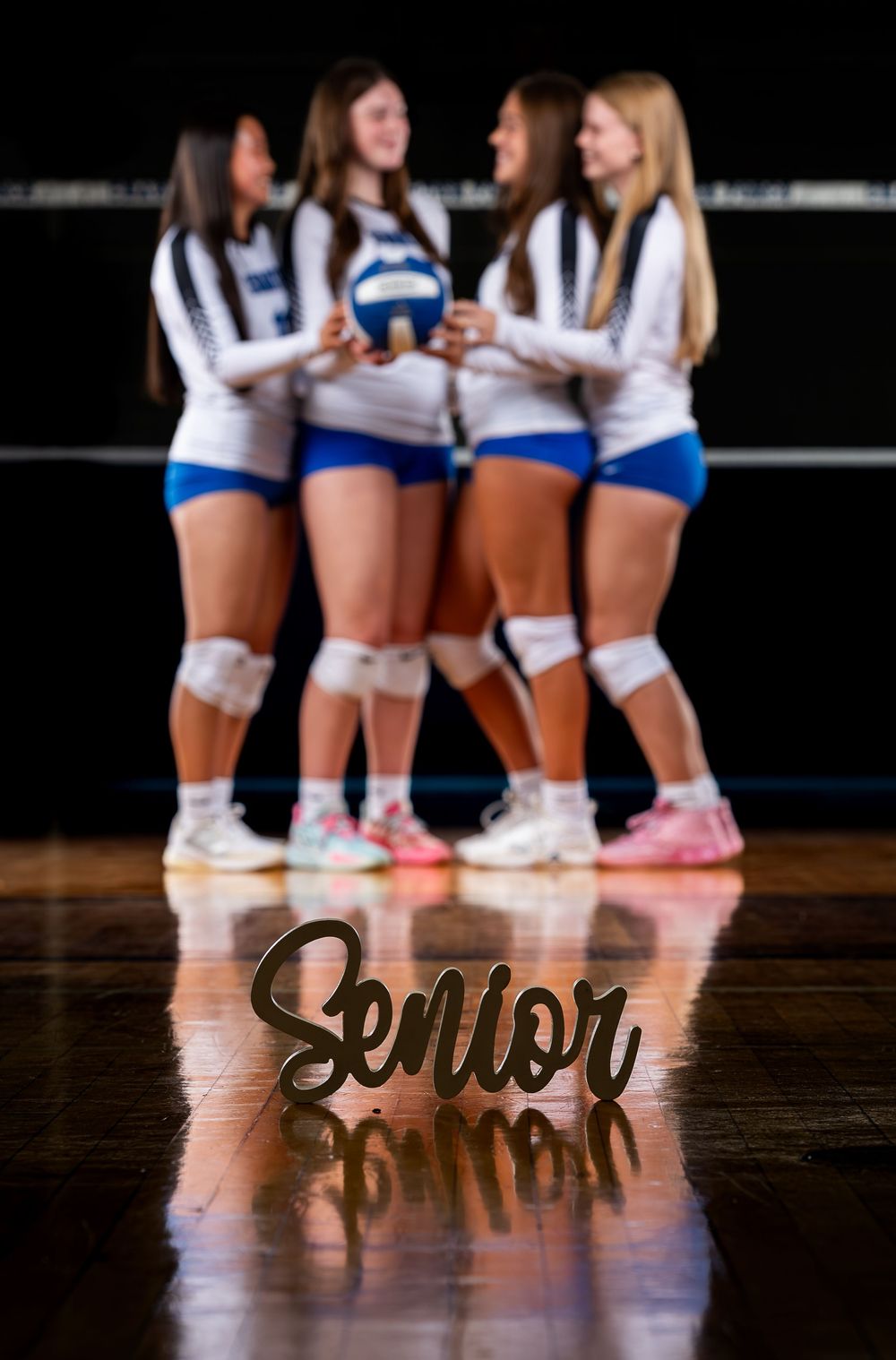 Athletes in volleyball uniforms huddle together while the word 'Senior' appears in script lettering in the foreground.