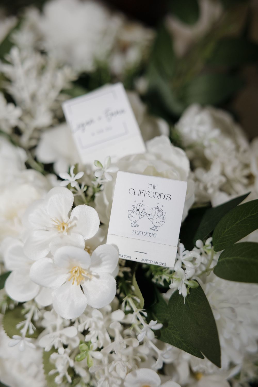 Elegant white floral bouquet with The Cliffords matchbook wedding favor and personalized cards.