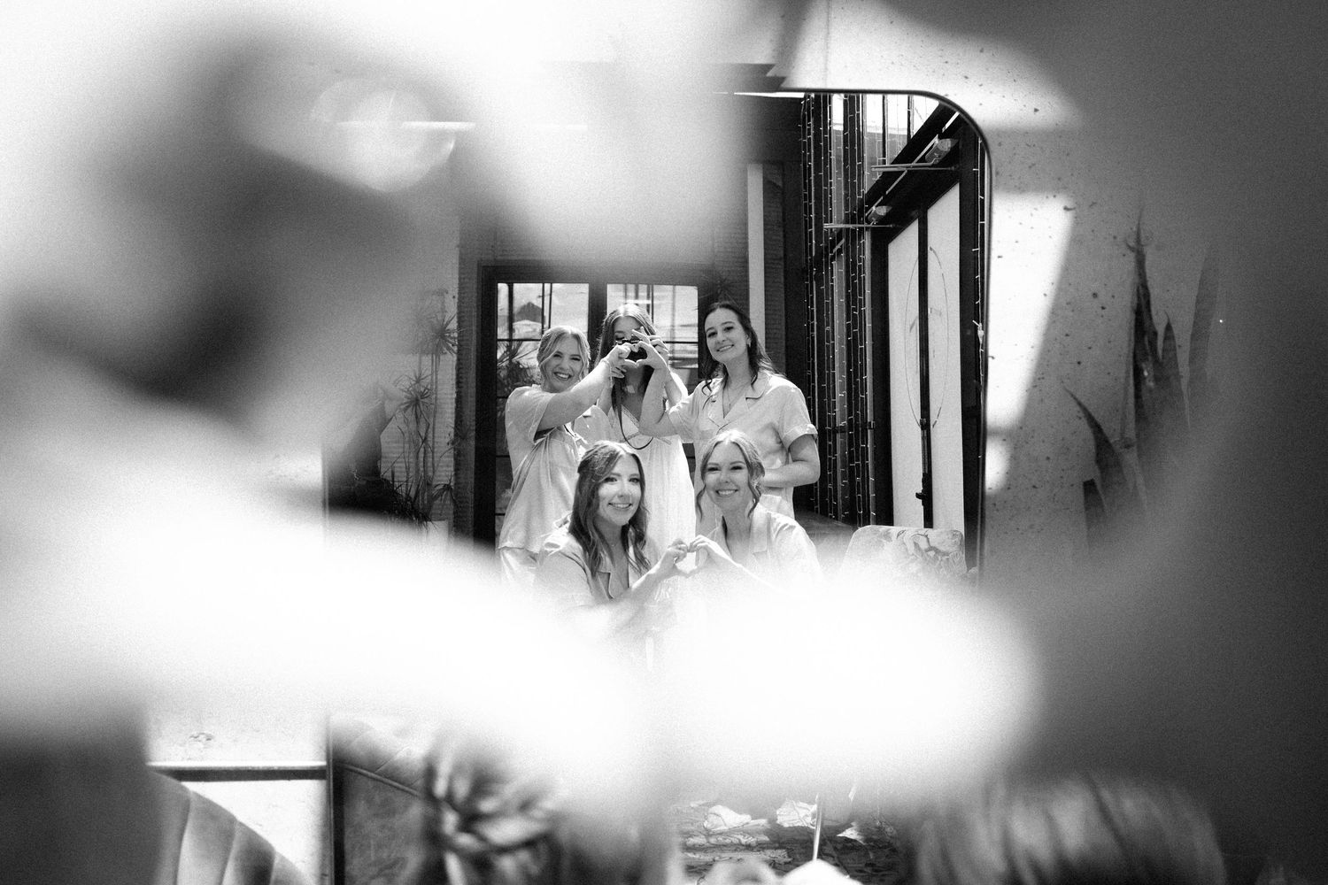 Black and white photo of bridesmaids laughing and getting ready together in a beautifully lit room.