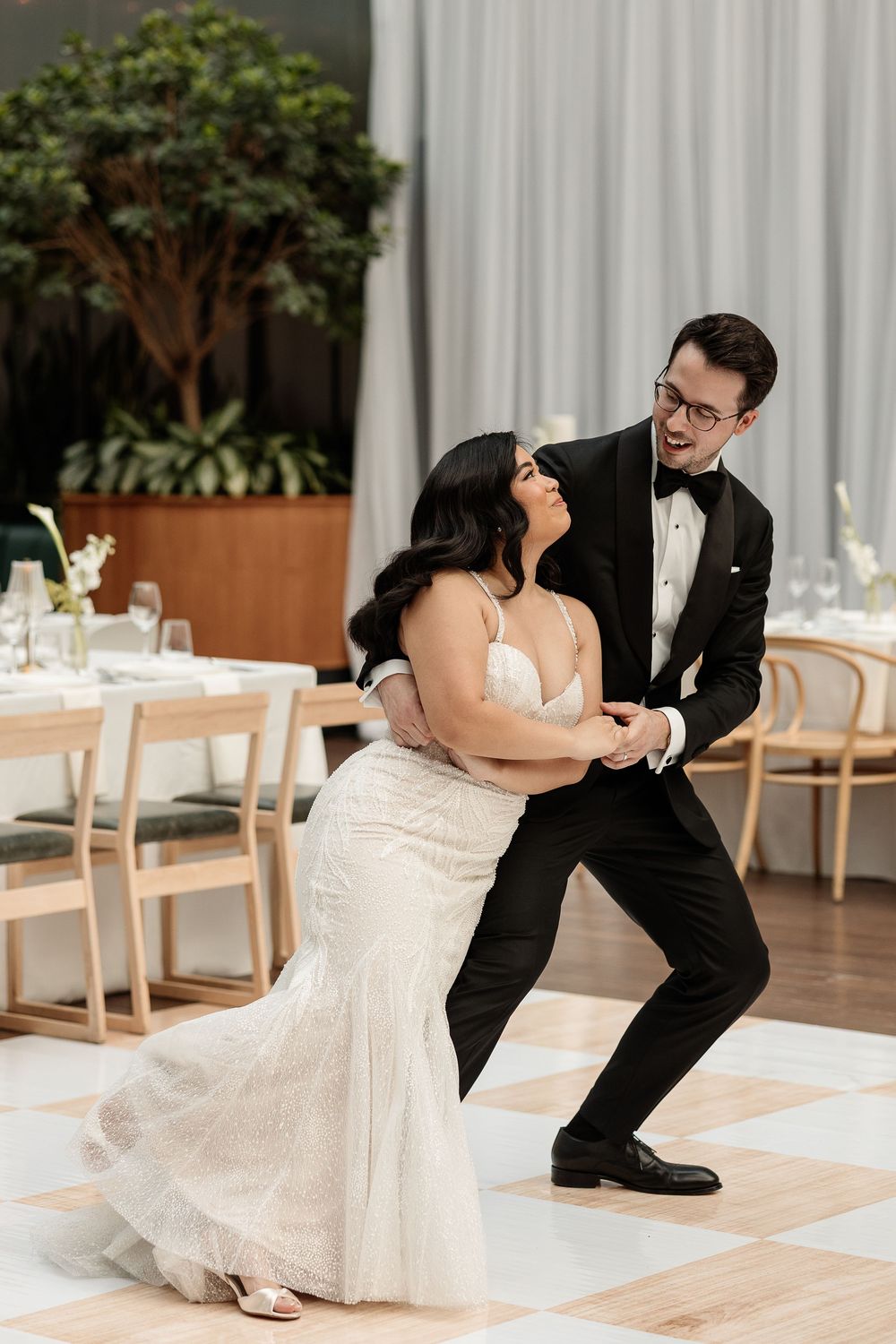 Bride and groom share a joyful first dance on a checkered floor in a modern wedding reception venue Le Cathcart in downtown Montreal.