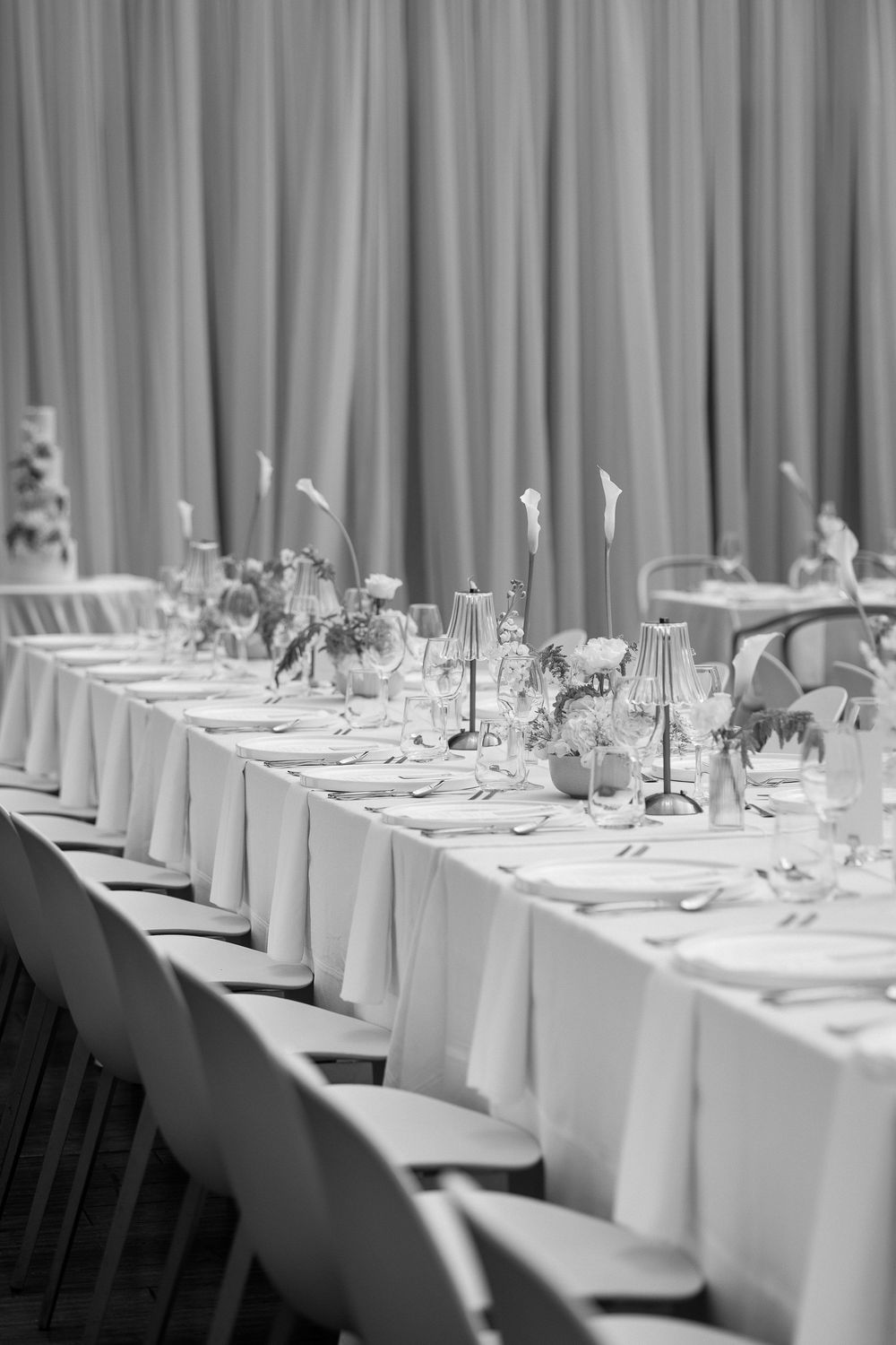 Elegant black and white photo of a long banquet table set with candles, flowers, and glassware for a formal event.