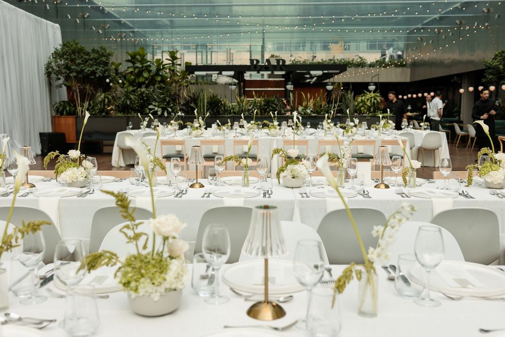 Elegant wedding reception with white tablecloths, florals, and string lights under a glass ceiling at Le Cathcart wedding venue Montreal.