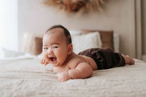 A baby lies on white bedding while looking up with a gentle expression in a series of connected photographs.一組連貫的照片中，一個嬰兒躺在白色床單上，抬頭望向天空，表情溫柔
