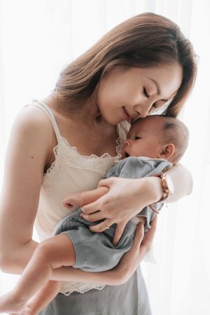 A tender moment between mother and baby as they share a gentle embrace in soft natural lighting.在柔和的自然光線下，母子倆溫柔地擁抱在一起，展現出溫馨的瞬間。