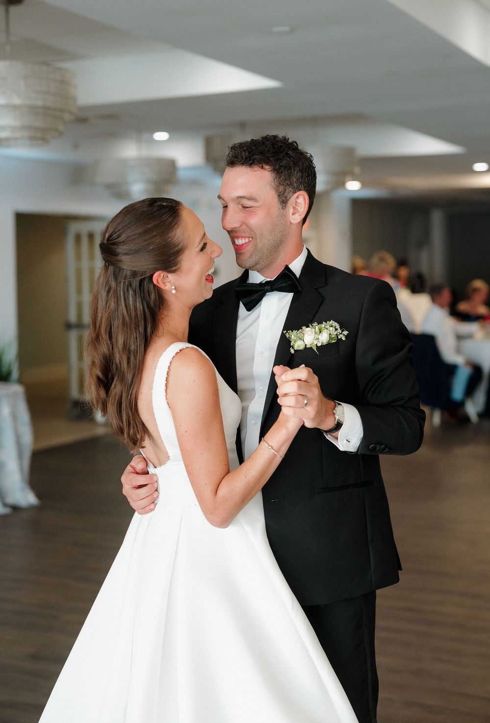 Bride and groom sharing their first dance at wedding reception in elegant white and black attire.