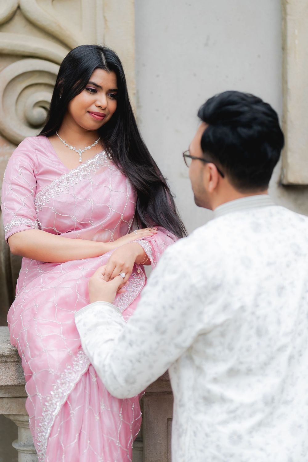 A woman in a pink saree and a man in white kurta share a romantic moment during an Indian pre-wedding photoshoot.