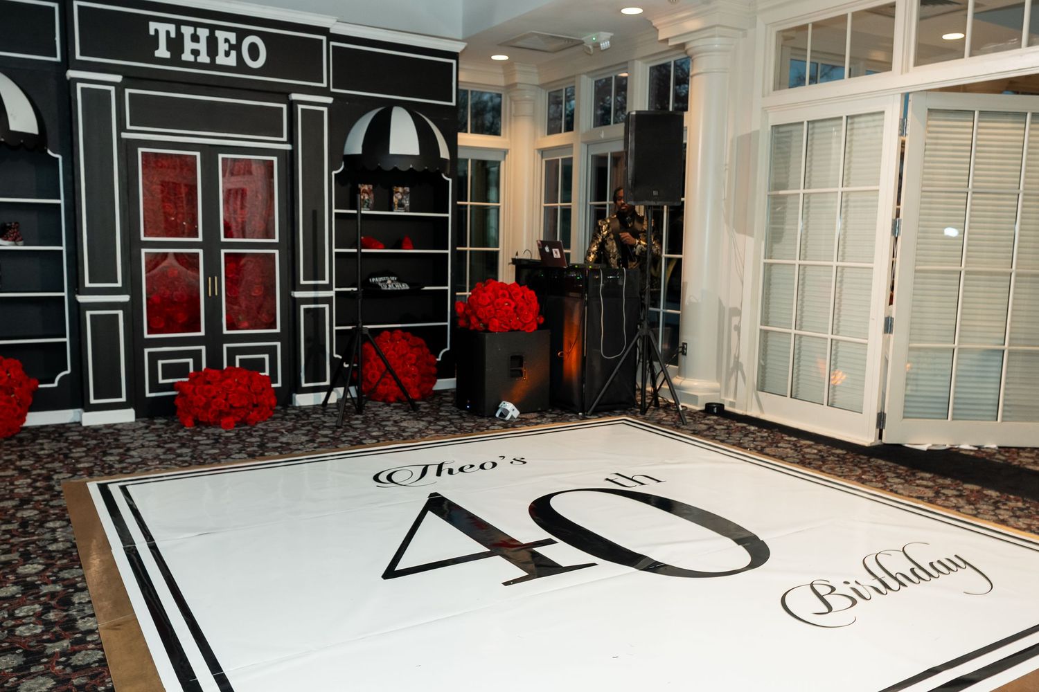 Elegant 40th birthday party setup with custom dance floor, black storefront backdrop, and red floral decorations. Deerfield Golf Club Newark