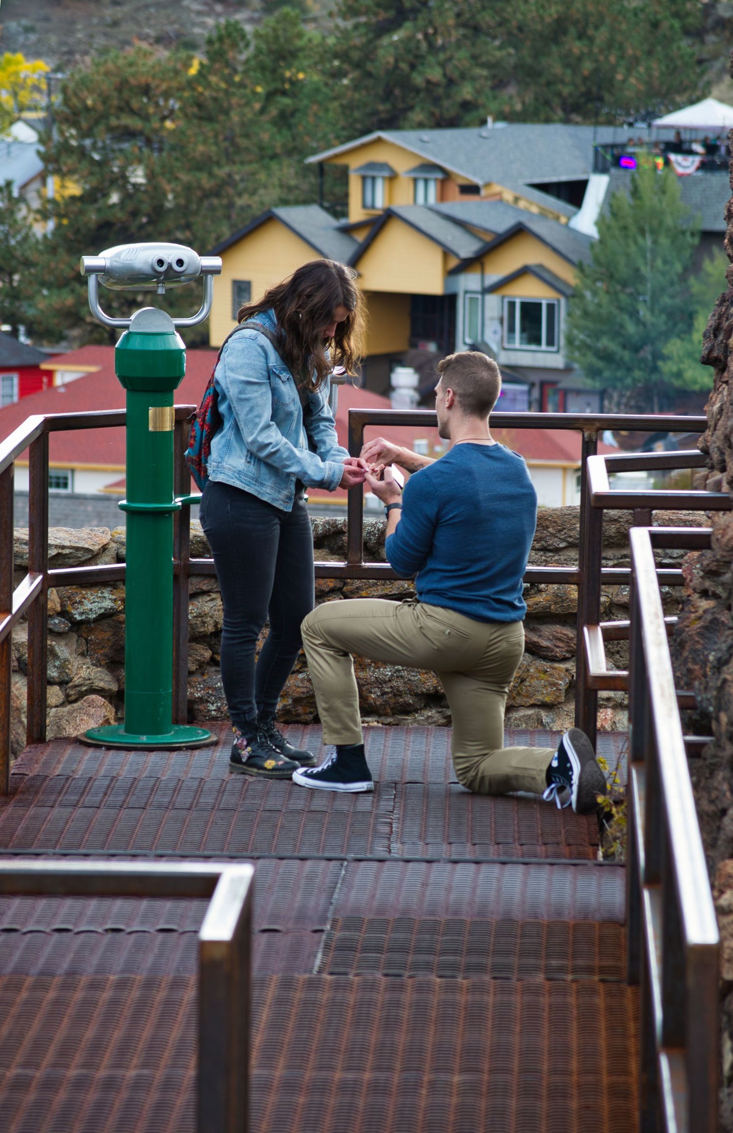 He slides the ring on her hand as she tries to contain the tears of joy after saying yes to his proposal.
