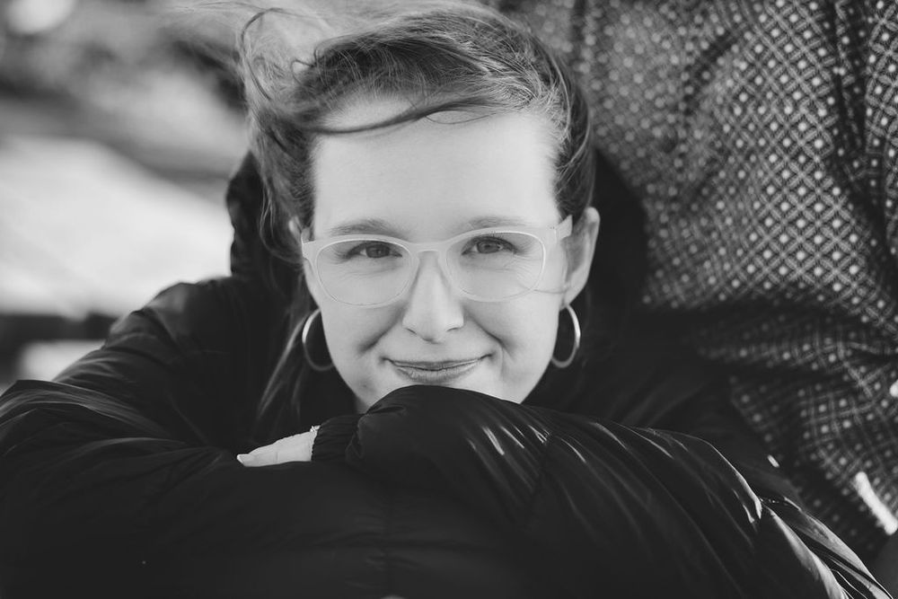 Black and white close-up portrait of a smiling young woman wearing hoop earrings.