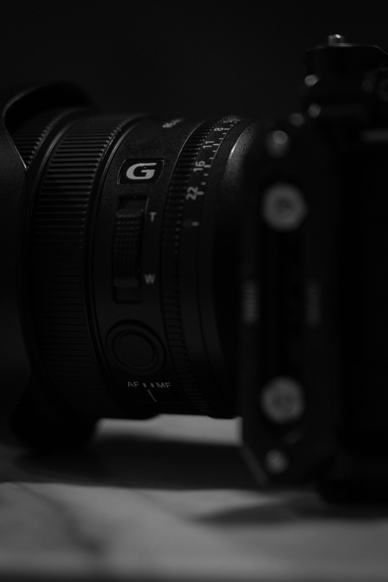 Close-up macro shot of camera lens markings and focus ring controls in dramatic black and white lighting.