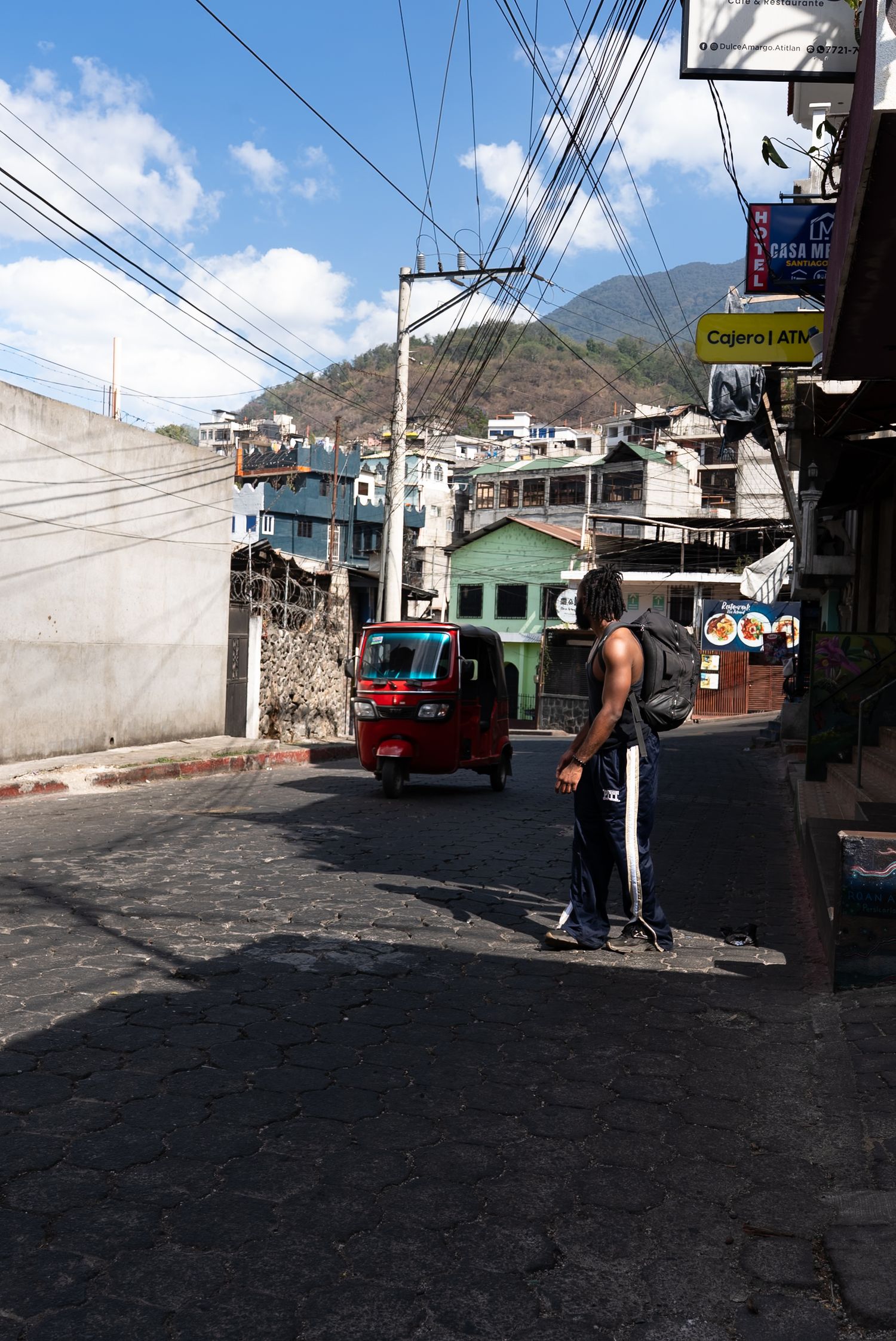 A sequence of street scenes in a mountainous town showing buildings, power lines, and a bus on a cobblestone road.