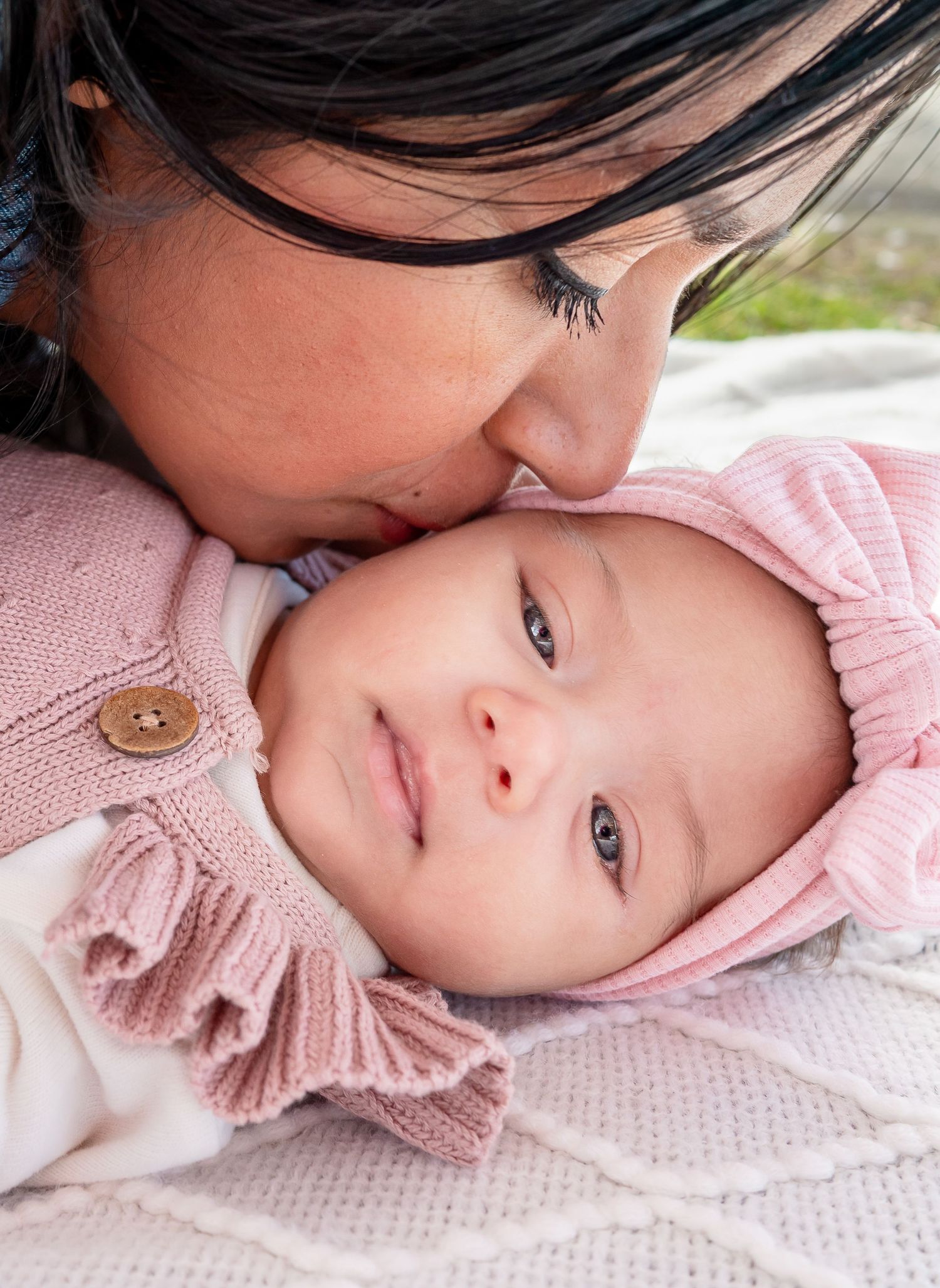 Mother kissing newborn under cherry blossoms in Seattle.
