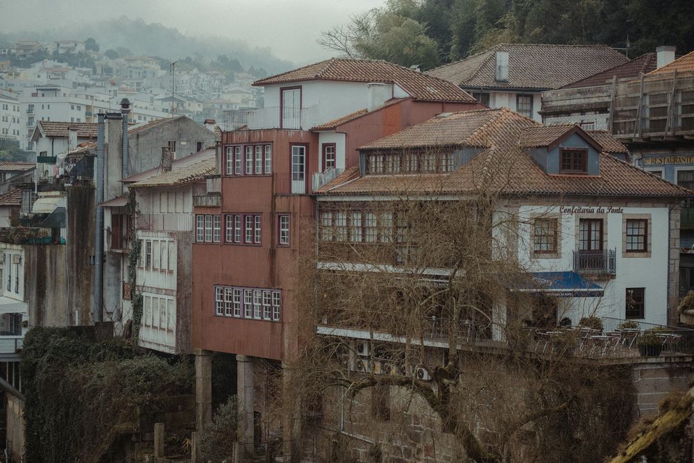 Historic hillside buildings with colorful facades and wooden balconies in a misty European town.