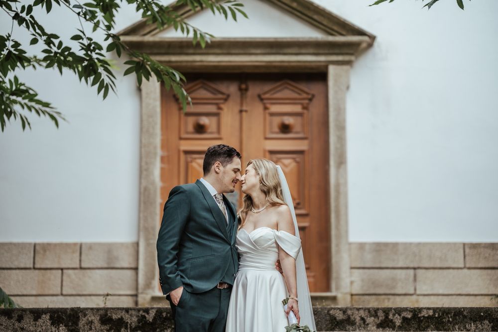 Bride and groom standing close together in front of an elegant wooden door, sharing an intimate wedding moment.