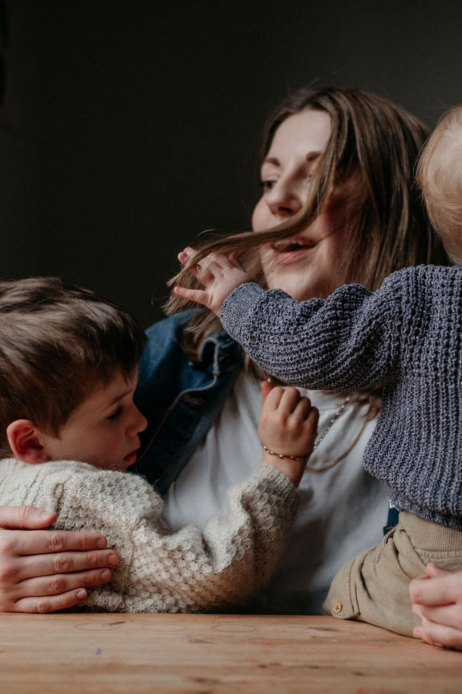 A mother laughing with her young child across a table, sharing a joyful and unscripted moment during a lifestyle family photography session.