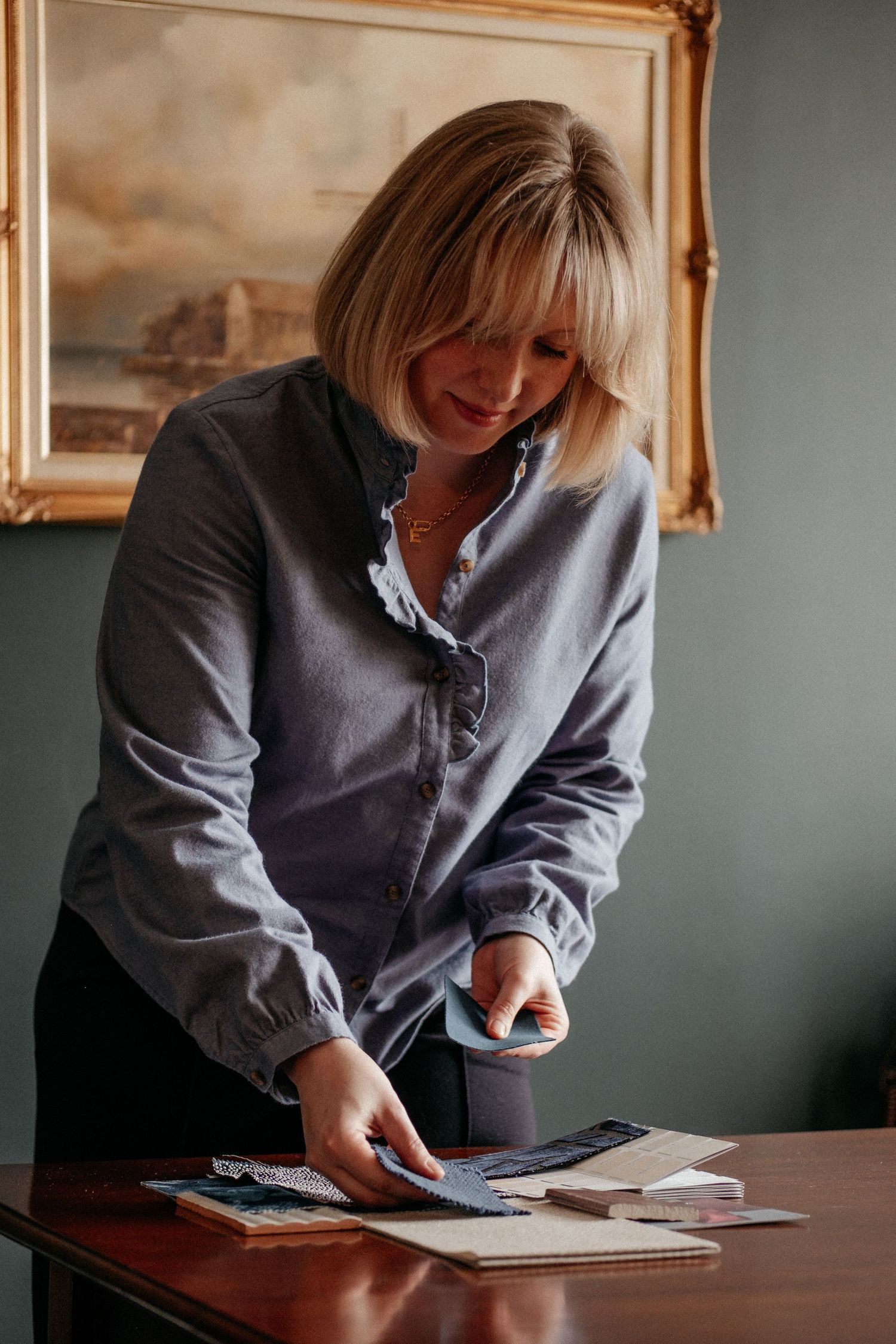 A woman leaning over a desk reviewing documents, captured in a natural, candid moment during a personal brand photography session.
