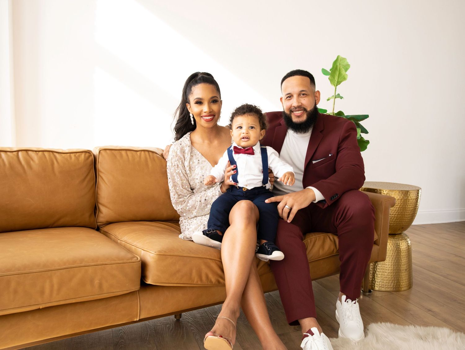 Family relaxing together on tan leather couch in modern living room interior.