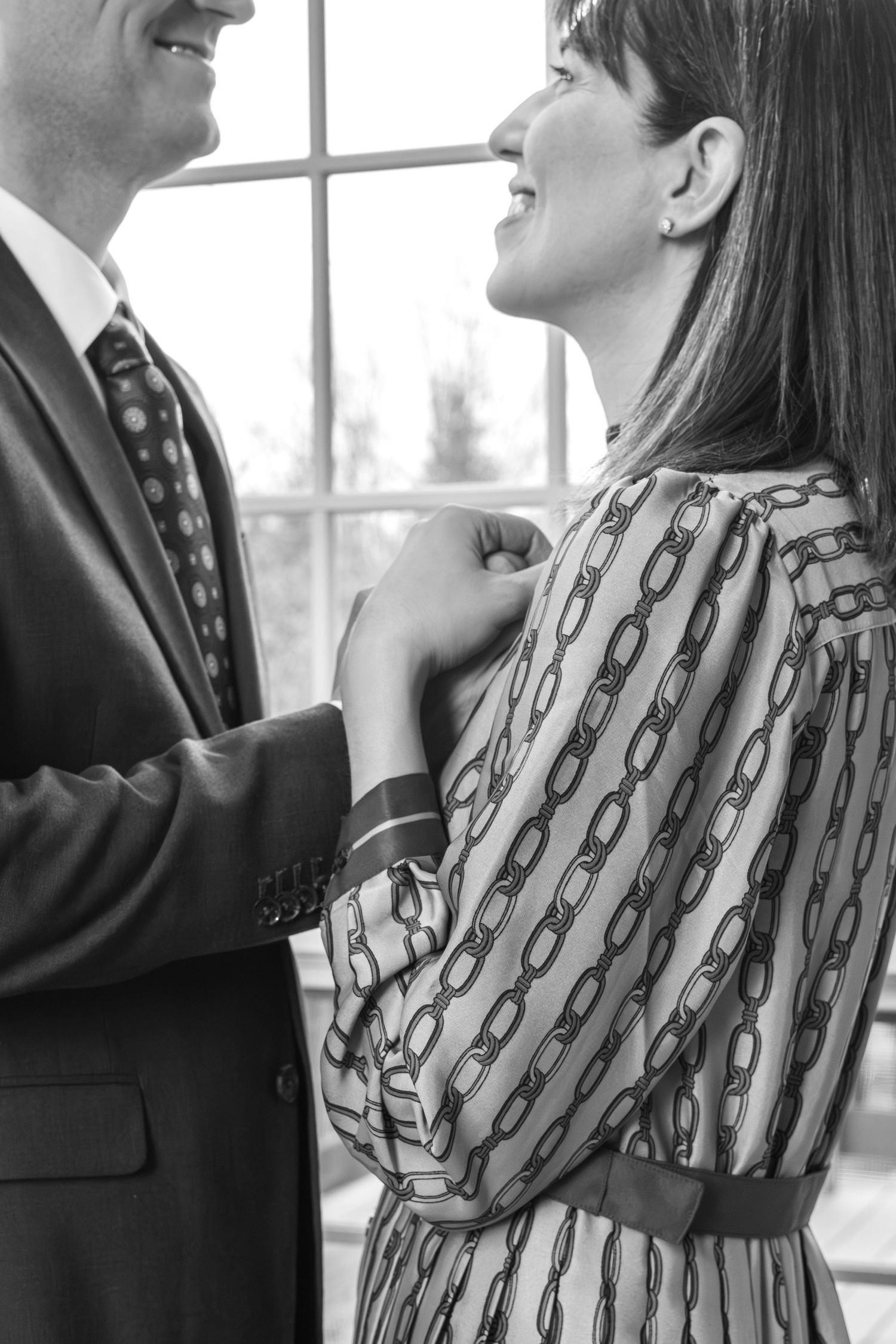 Black and white image of two people dressed in business attire standing close together by a window. Grand Rapids Michigan.