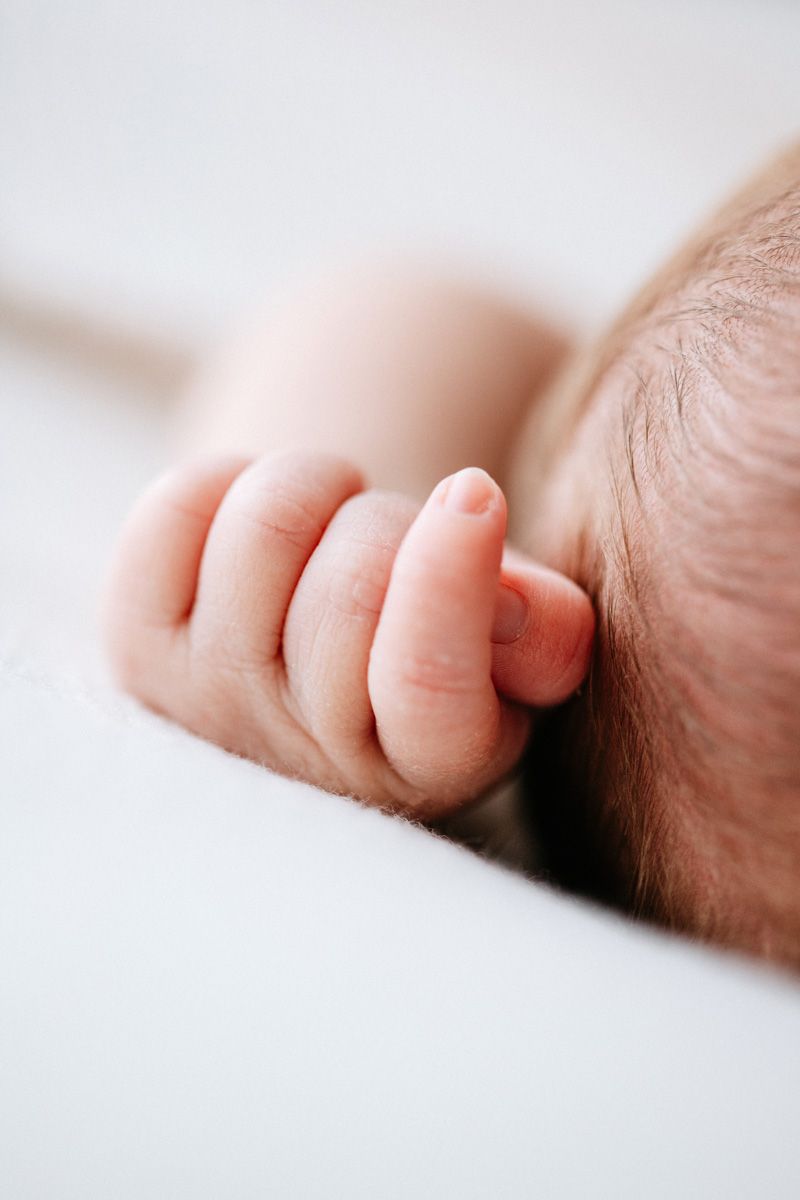 Close-up macro photograph of a baby's tiny fingers against a soft white background.