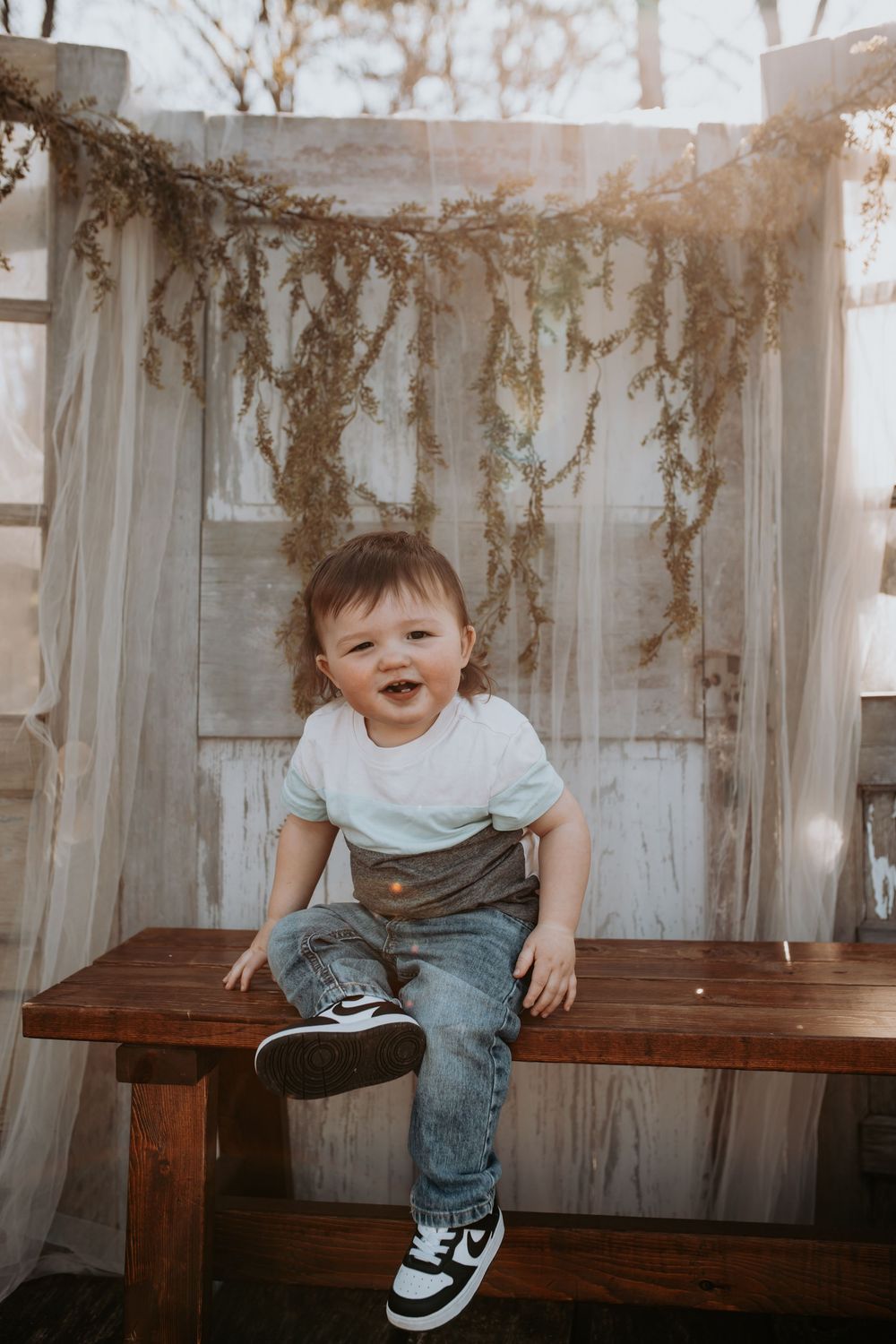 Candid moments on a rustic wooden bench with dried vines in background.
