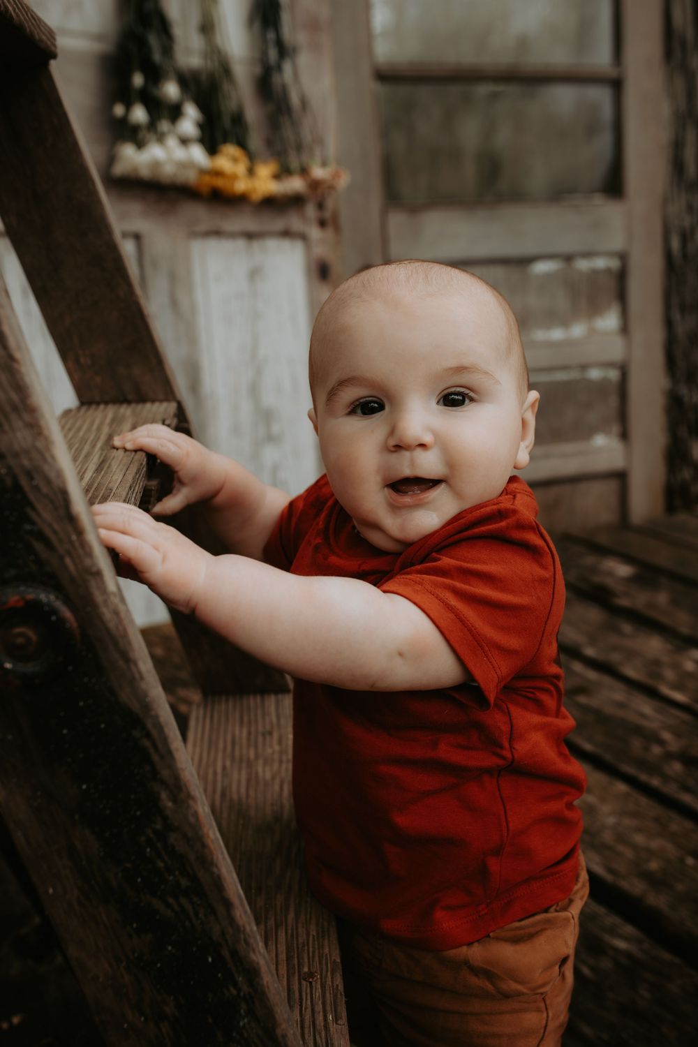 Joyful expressions shown while wearing a red shirt near wooden structures.