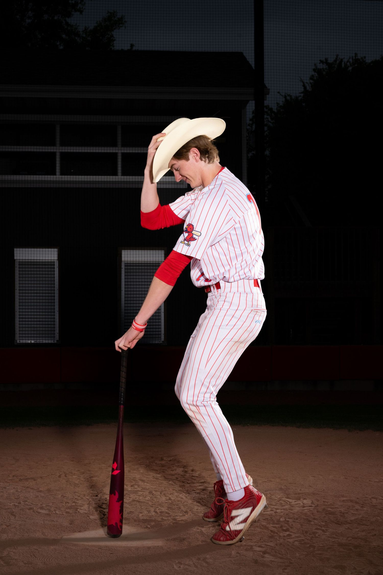 Baseball player in pinstriped uniform demonstrates pitching form at night.