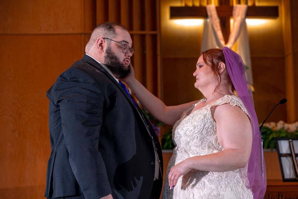 A couple shares an emotional moment together during their wedding ceremony in a wood-paneled venue.