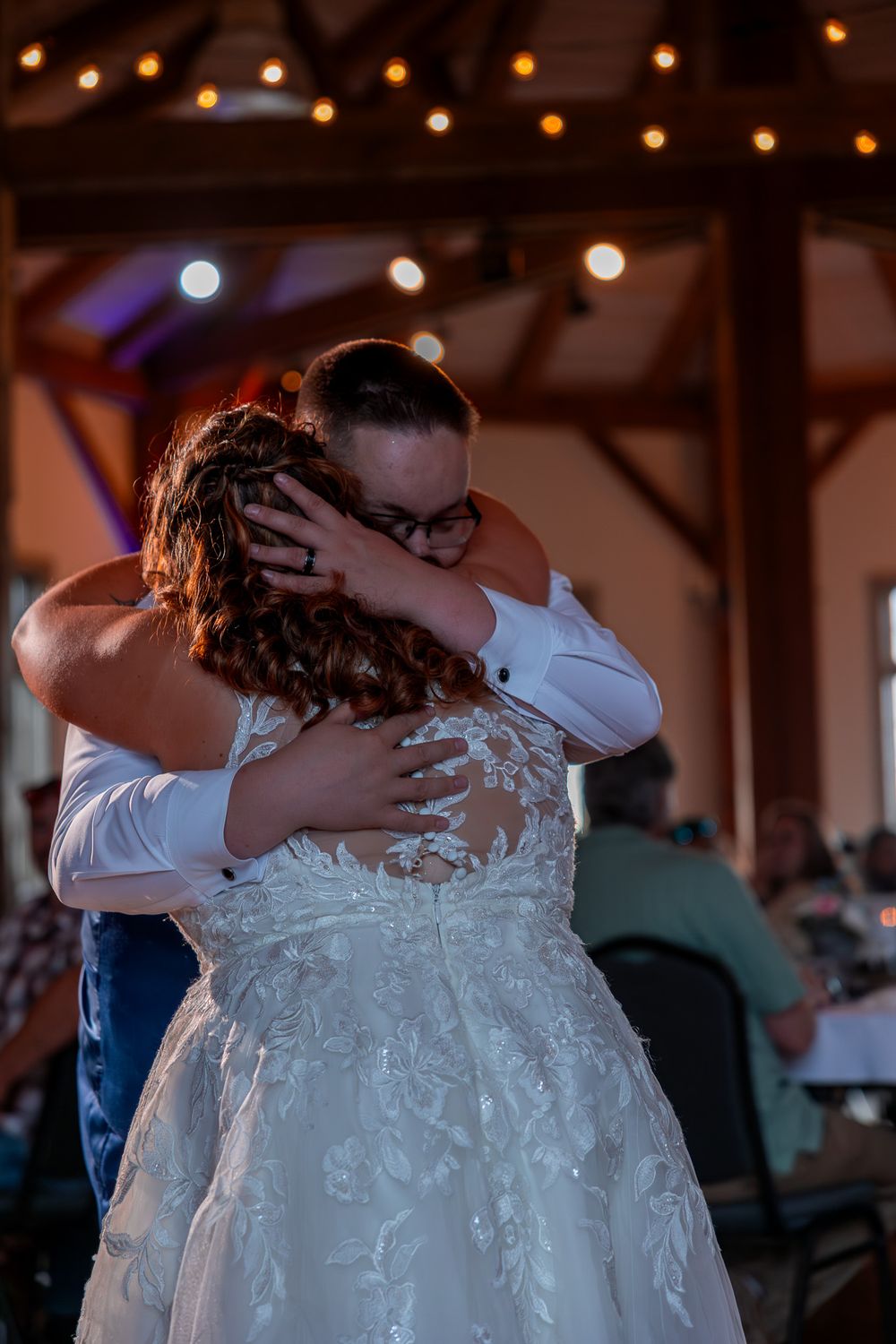 An intimate embrace on a wedding dance floor with string lights twinkling overhead.