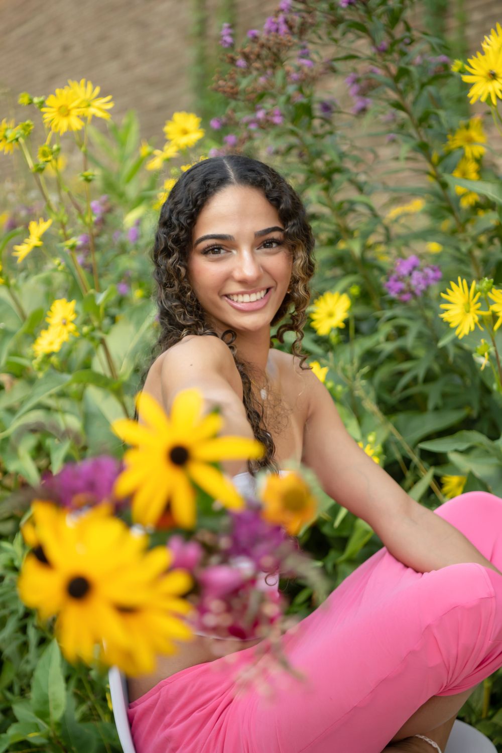 A portrait among vibrant yellow sunflowers and purple wildflowers in a garden setting.