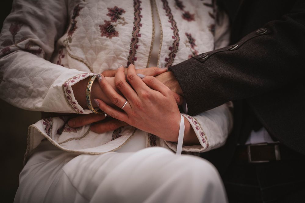 A close-up detail shot of hands clasped together during a traditional ceremony.