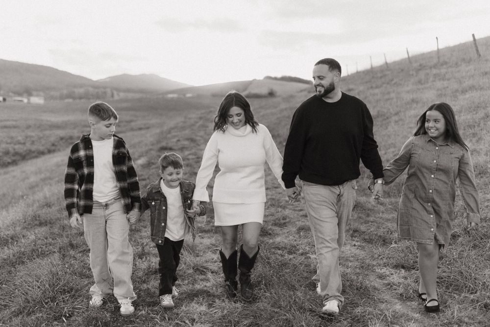 Black and white photo of family walking together through rolling countryside.