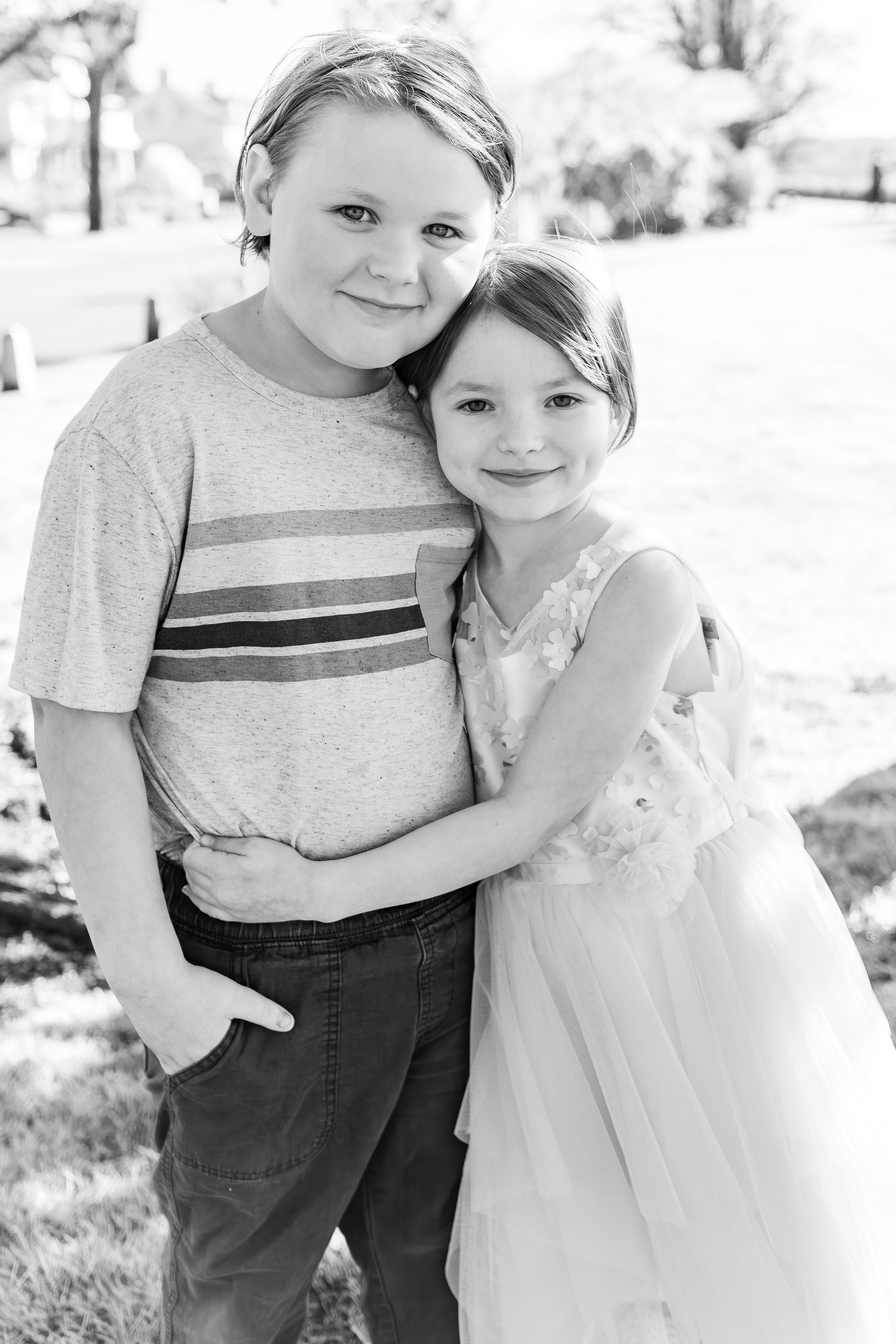 Two children hugging and smiling in black and white portrait.