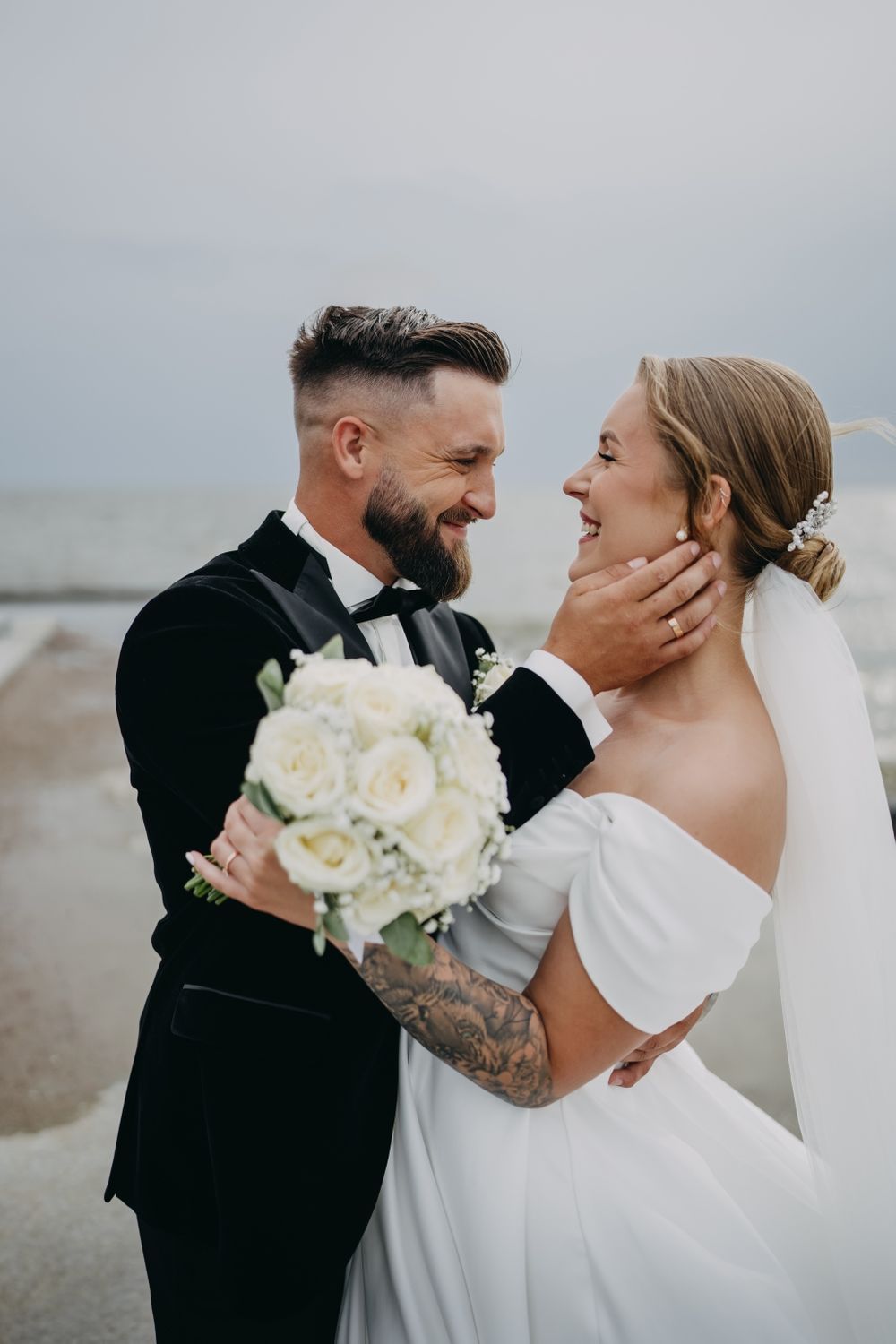 Intimate wedding couple moments captured against overcast coastal backdrop.