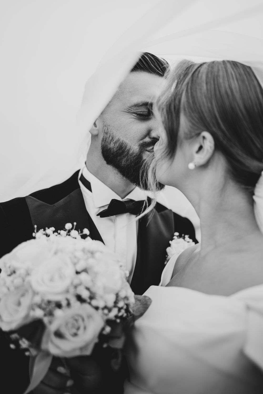 Black and white wedding photos showing romantic close-up moments with a bouquet of roses.